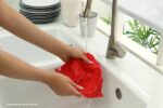 keuken schoon: een persoon die een rode doek schoon spoelt onder stromend water