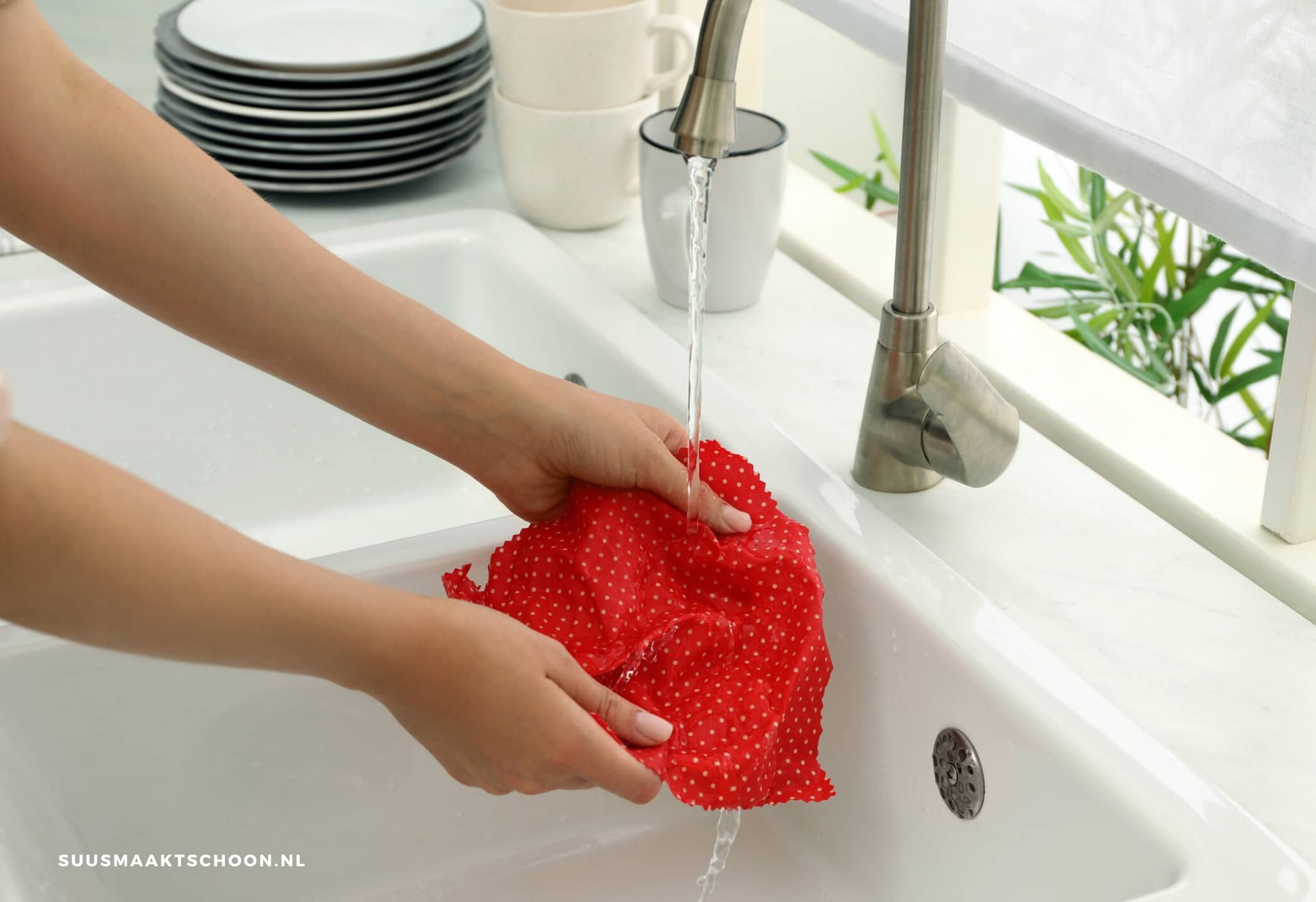 keuken schoon: een persoon die een rode doek schoon spoelt onder stromend water
