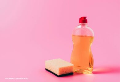 schoonmaken met afwasmiddel: afwasmiddel en een schuurspons met roze achtergrond