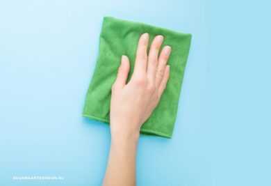 Hand met groene microvezeldoek: scoonmaken met microvezeldoekjes