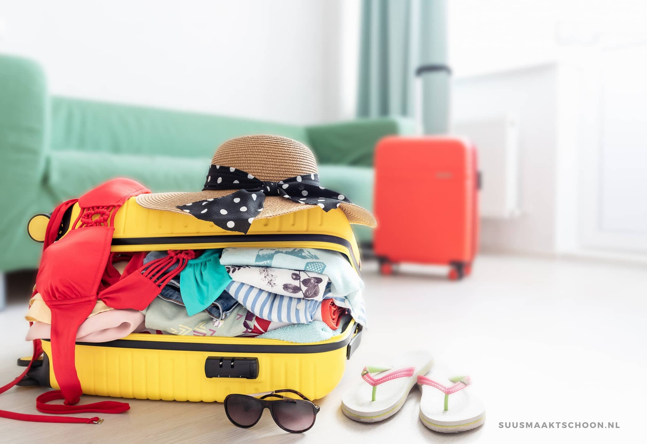 huis oprumen voor vakantie: een overvolle koffer met een hoed erop en slippers ernaast