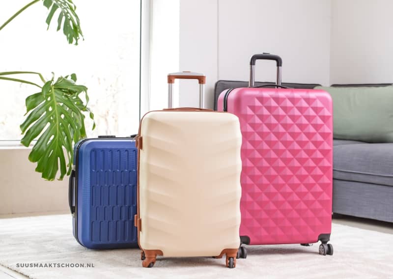 huis opruimen voor vakantie: drie koffers in een lege woonkamer