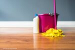 laminaatvloer schoonmaken: een dweil en een emmer op een houten vloer
