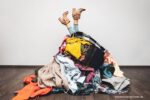opruimmethodes: een stapel kleren waar benen uitsteken