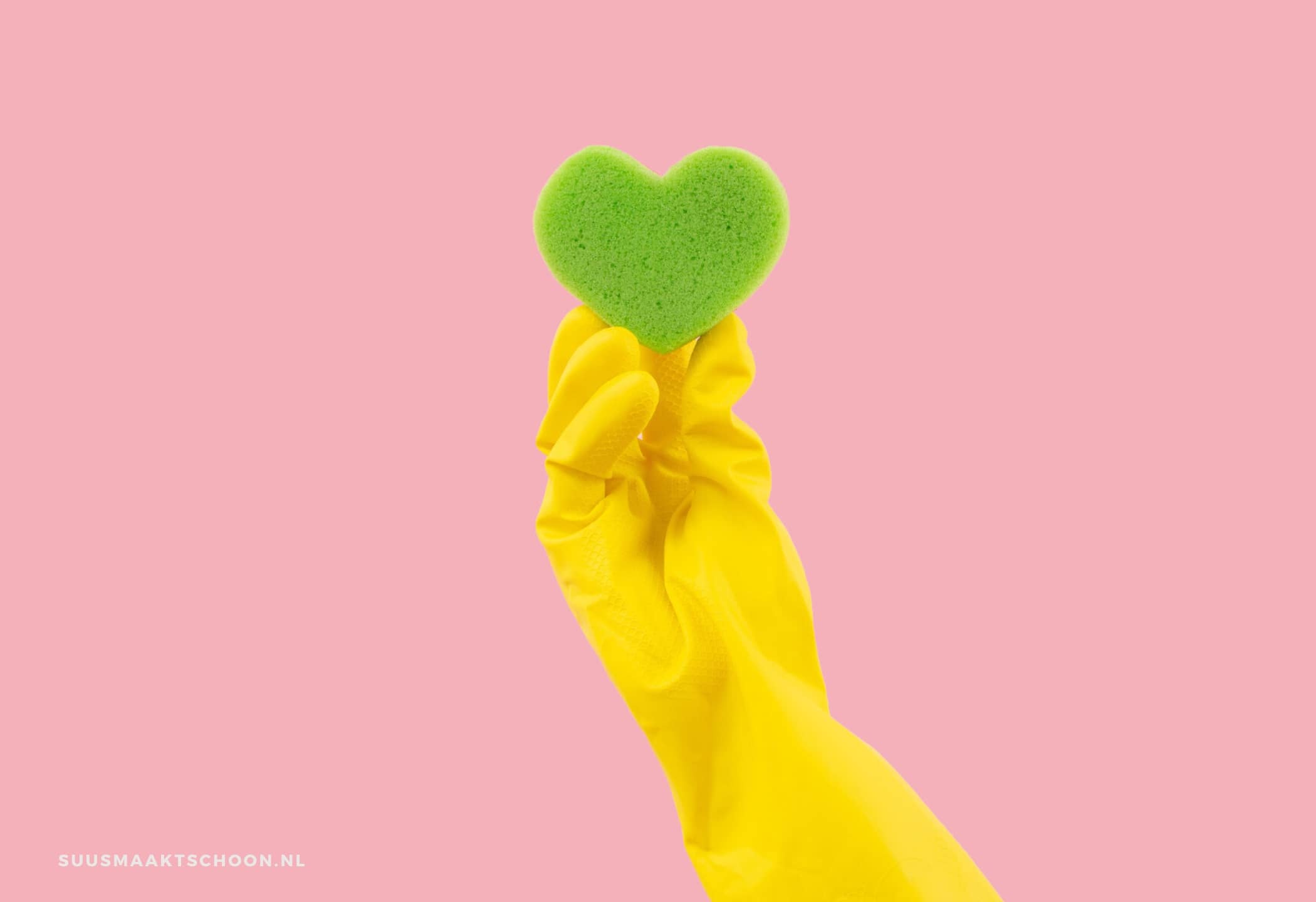 spons in de koelkast: een hand in een gele handschoen die een groene hartvormige spons vasthoudt