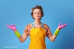 mindful schoonmaken: een vrouw met een geel schort en roze handschoenen