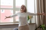 een vrouw met uitgestrekte armen: ze is blij want ze heeft een opgeruimd huis