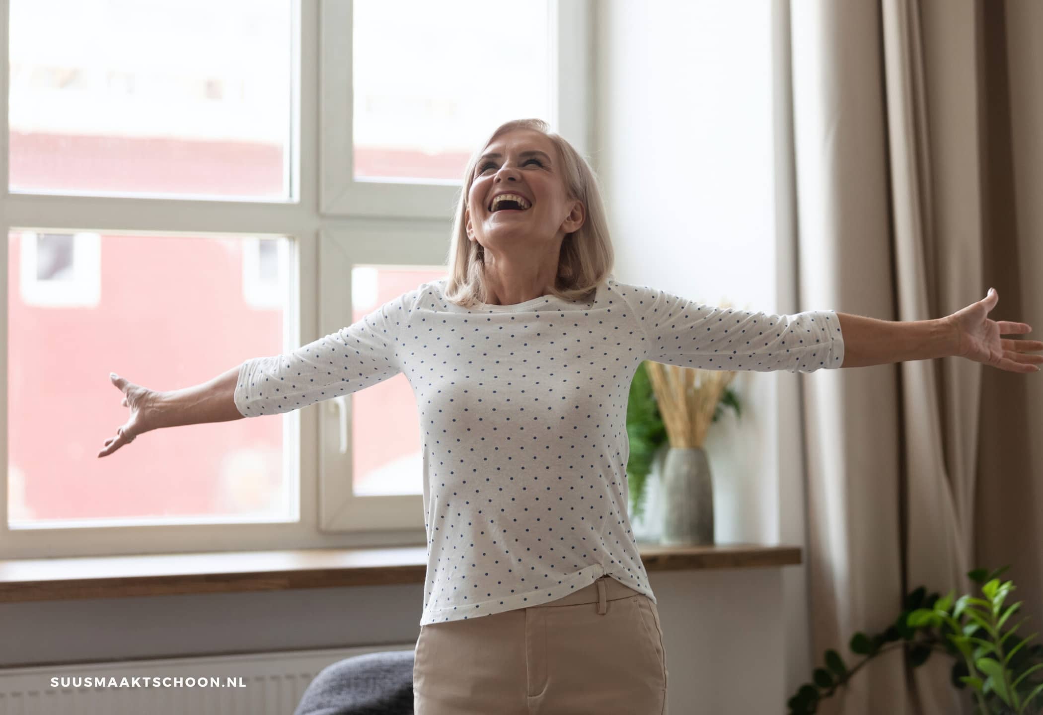 een vrouw met uitgestrekte armen: ze is blij want ze heeft een opgeruimd huis