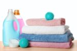 Nadelen van wasverzachter: een stapel handdoeken en wasmiddelen, waaronder wasverzachter