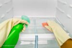 afvoergaatje koelkast verstopt: persoon maakt koelkast schoon