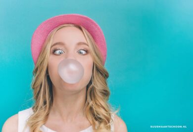 Kauwgom uit kleding: een vrouw die een bel blaast van kauwgom