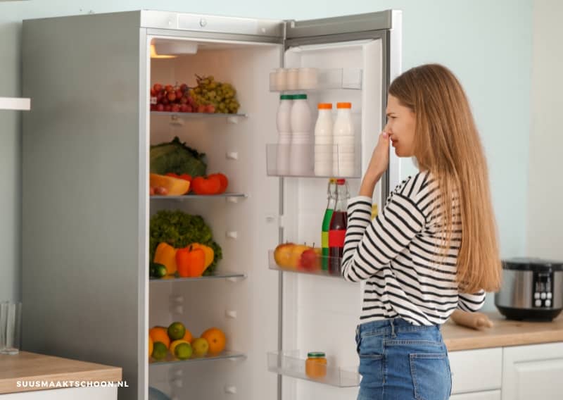 Koelkast stinkt: een vrouw die in een koelkast kijkt