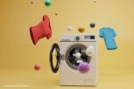 Beste wasmiddel voor gekleurde was: een wasmachine met kleurrijke ballen en shirts die in de lucht zweven