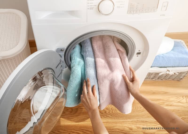 handdoeken wassen: een persoon die handdoeken in een wasmachine doet