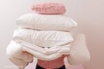 wassen van beddengoed: een persoon met een stapel kussens en dekens