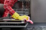 afwasmachine schoonmaken: vrouw maakt vaatwasser schoon