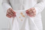 vetvlekken uit kleding: persoon houdt kledingstuk vast met vetvlekken