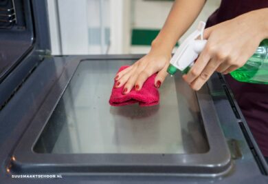 vrouw ovenruit schoonmaken met donkerroze doek
