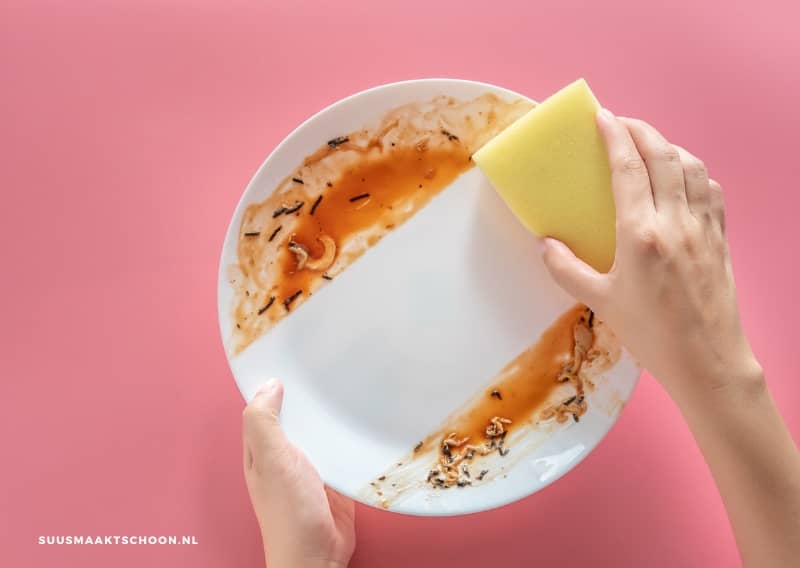afwassen met koud water: een persoon die een bord schoonmaakt