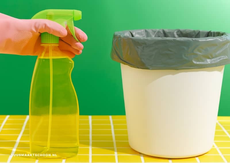 Brandschoon huis: een hand met een spuitfles naast een witte vuilnisbak