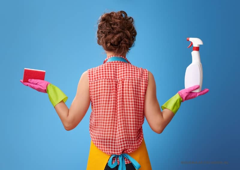 Vies huis: een vrouw met een schoonmaakmiddel en een spons in de hand