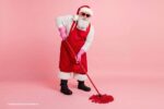 Schoonmaken voor de feestdagen: kerstman die dweilt, roze achtergrond