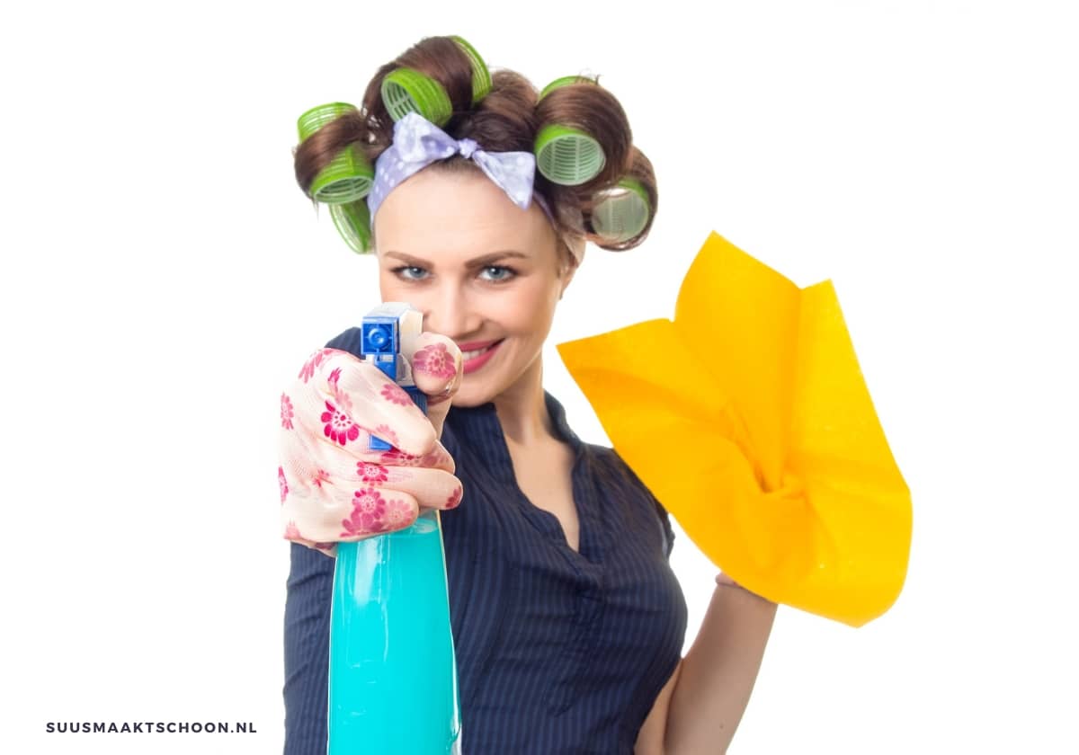 Vrouw met schoonmaakspullen die een sprayfles vasthoudt, symbool voor schoonmaken met water, passend bij waarschuwing om bepaalde materialen nooit met water te reinigen.