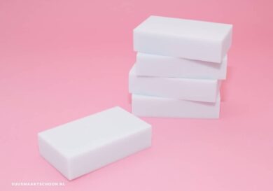 Vijf witte melaminesponsjes, roze achtergrond, schoonmaken met wondersponsjes