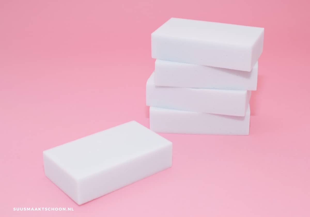 Vijf witte melaminesponsjes, roze achtergrond, schoonmaken met wondersponsjes