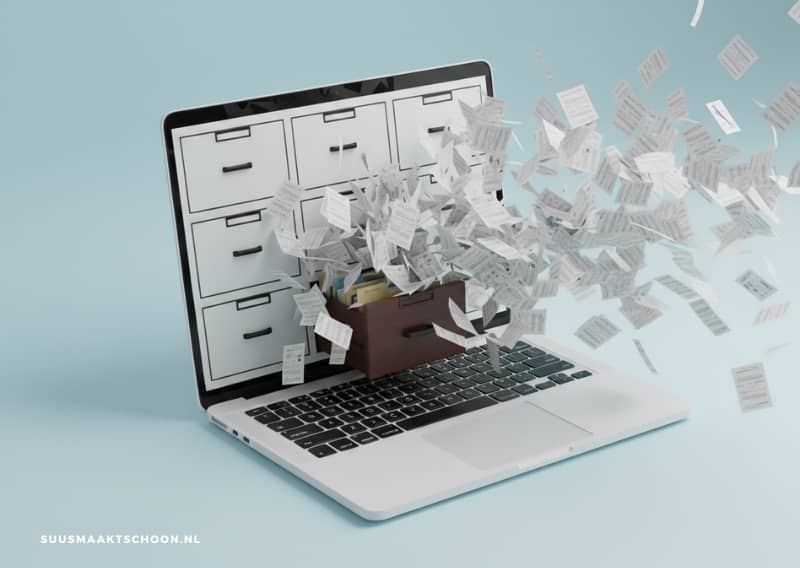 Laptop met open digitale lade waar losse documenten uit wegvliegen, als beeld voor digitale chaos en het belang van digitale bestanden organiseren met slimme apps.