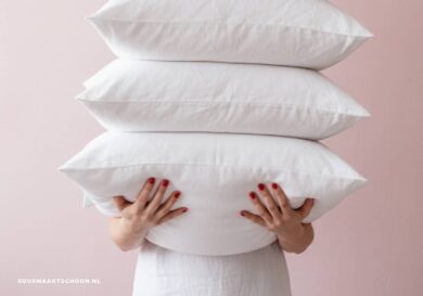 Vrouw met stapel witte hoofdkussens na hoofdkussen wassen